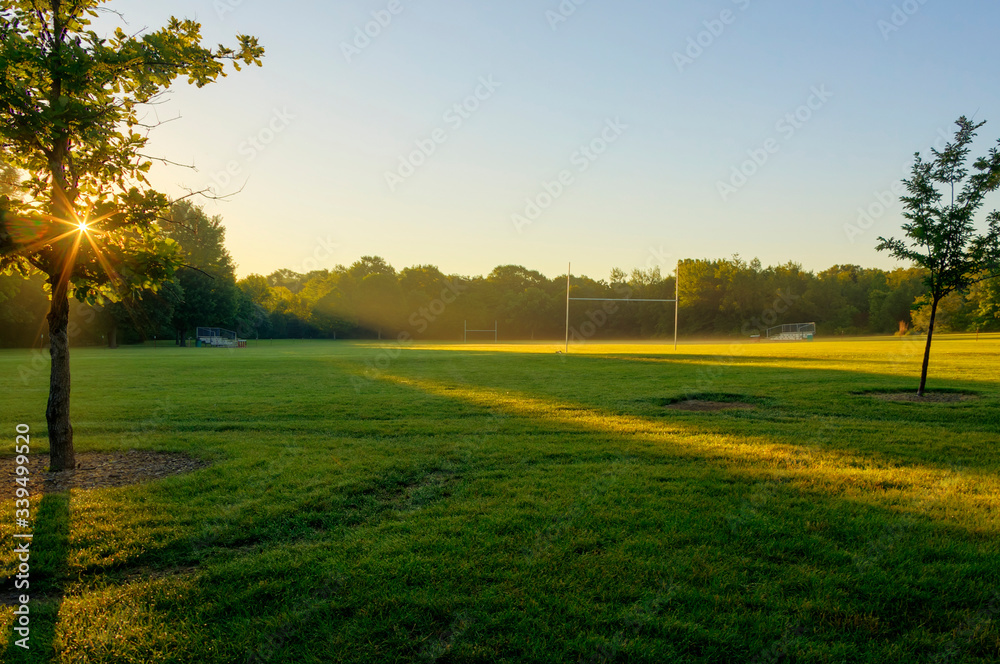 dawn breaking over a football field in a city park
