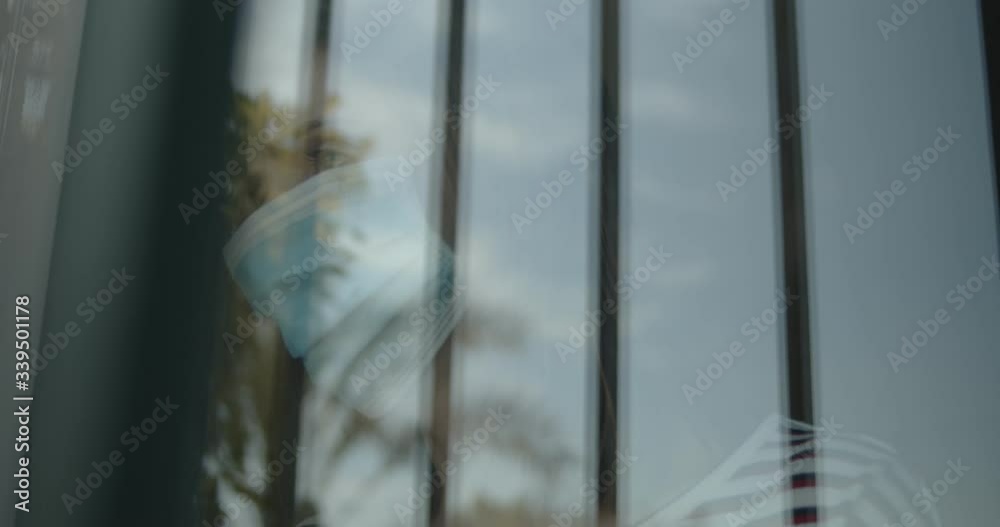 Mujer mirando a través de la ventana con una mascarilla durante la pandemia del Covid-19 o Coronavirus