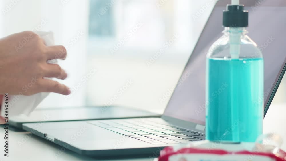 Asian woman using alcohol spray on tissue clean laptop before open for protect coronavirus. Female clean computer for hygiene when social distancing stay at home and self quarantine time. Asian woman using alcohol spray on tissue clean laptop before open for protect coronavirus. Female clean computer for hygiene when social distancing stay at home and self quarantine time.