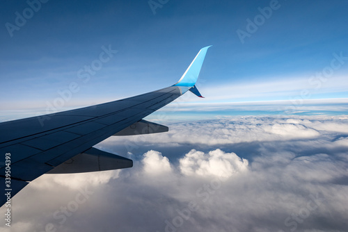 Commercial airplane while flying above the clouds. Aircraft wing view through the window