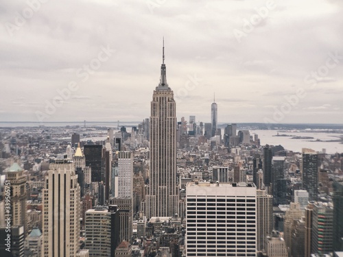 Платно Empire State Building And Cityscape Against Cloudy Sky
