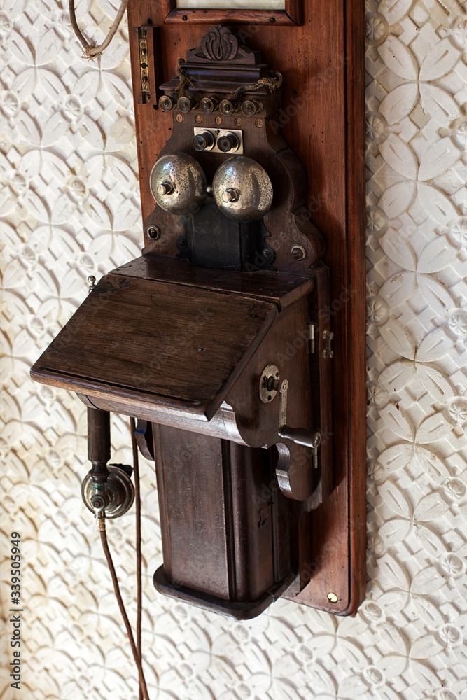 A vintage antique wooden telephone hangs on a wall.