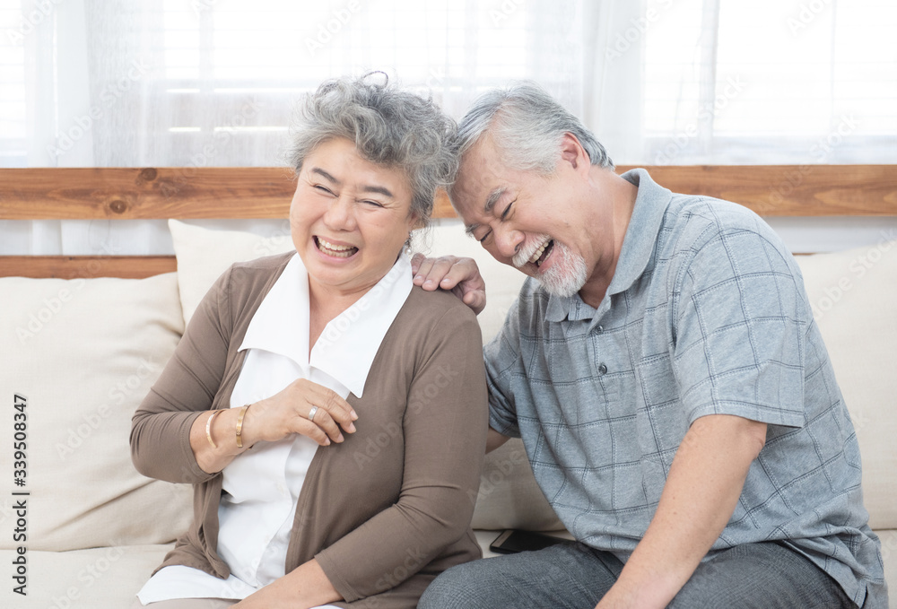 senior old asian couple laugh sit on sofa at home