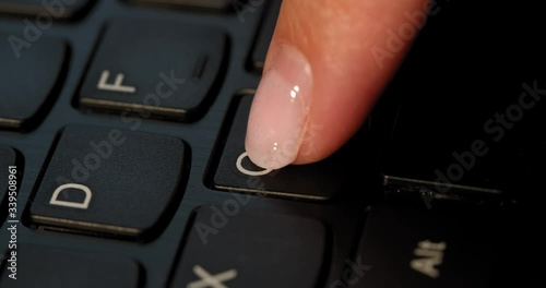 Black keyboard and a girl presses C button. English letters. Slow-mo and girl has a pink nail polish. photo