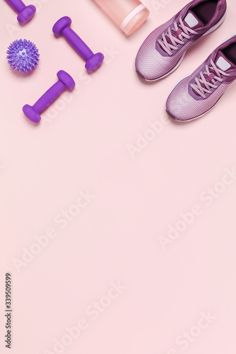 Sports equipment for women's training in pastel colored. Pink background, vertical picture.