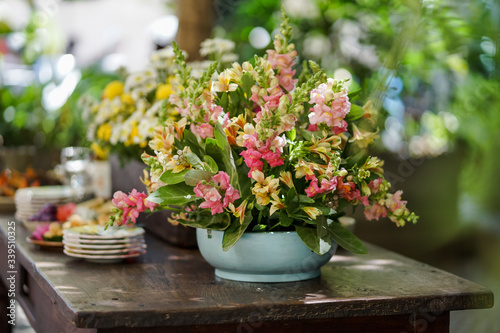Colorful flower arrangements are set up on a wooden table.