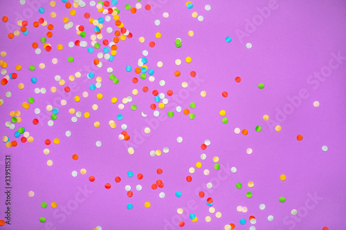 Purple background with vivid confetti. Colorful abstract backdrop with scattered paper circles. Beautiful decor for the party. Festive composition for celebration. View from above. Flat lay