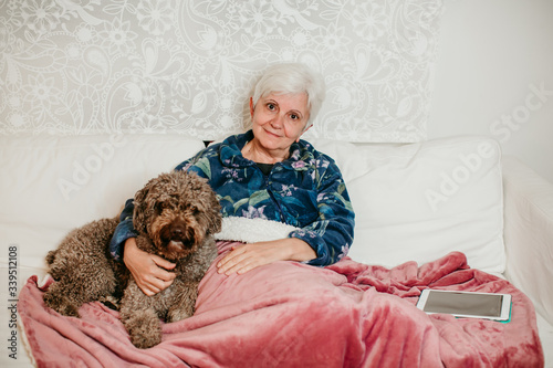 .Older woman accompanied by her loving dog at home during the quarantine season caused by covid 19. Not alone. Risk population. Lifestyle