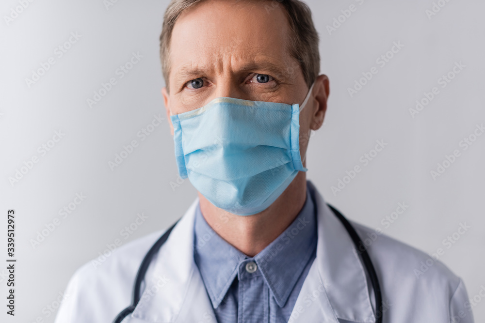 middle aged doctor in blue medical mask on grey middle aged doctor in blue medical mask on grey
