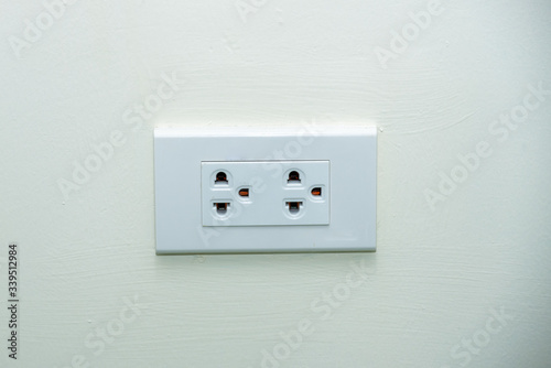 White wall socket on wall, electric socket with one button, Power outlet on white wall.
