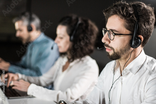 Concentrated bearded call center operator working. Thoughtful call center operators during working process. Call center concept