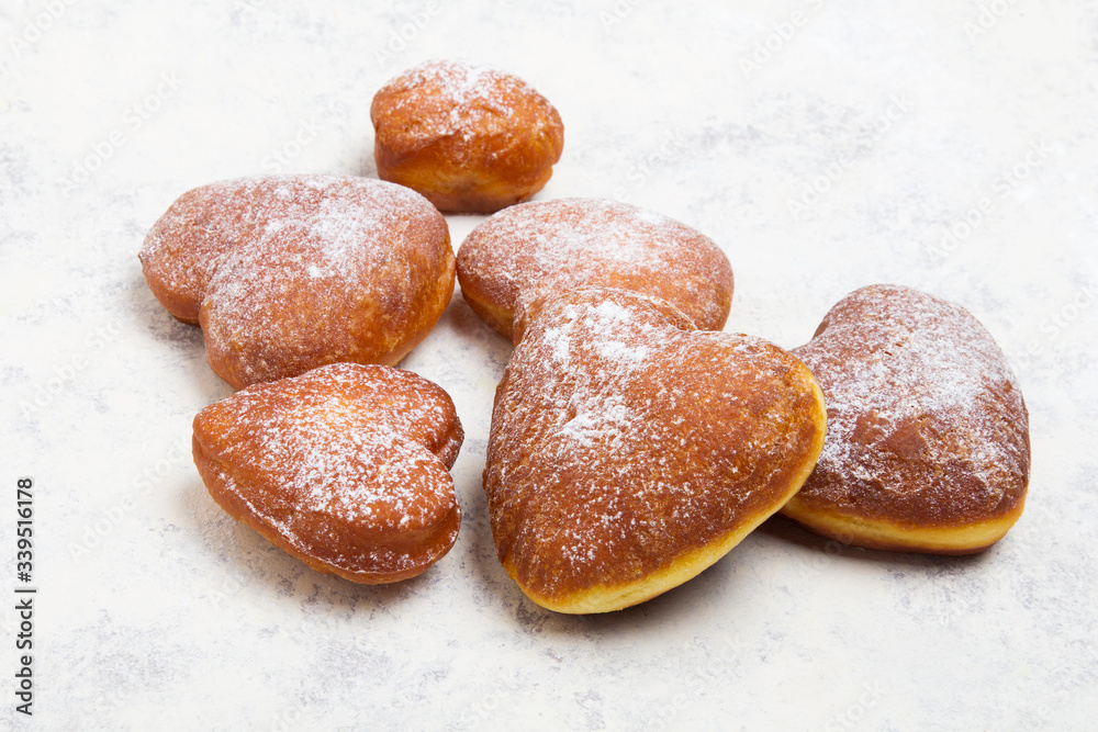 Homemade heart sheped donuts with powdered sugar on white background. Tasty doughnuts, copy space Homemade heart sheped donuts with powdered sugar on white background. Tasty doughnuts, copy space