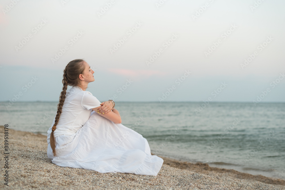 Young beautiful woman sitting on sandy beach against sea and dreams. keep calm Young beautiful woman sitting on sandy beach against sea and dreams. keep calm