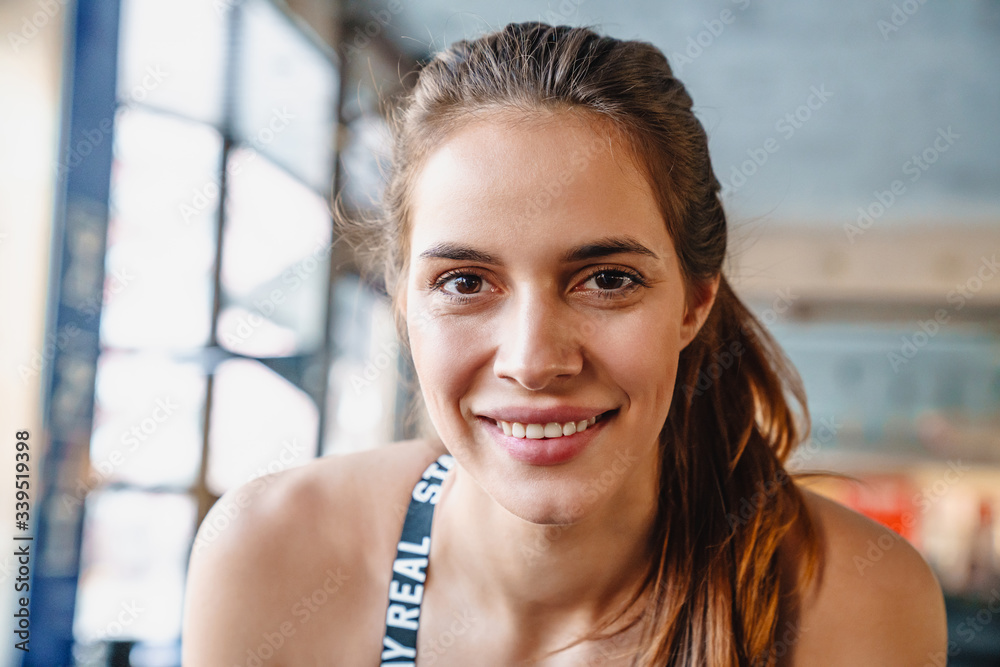 Portrait of cheerful nice sportswoman smiling and looking at camera