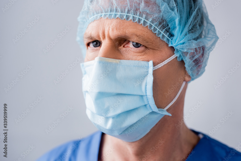mature doctor in blue medical mask and cap isolated on grey mature doctor in blue medical mask and cap isolated on grey
