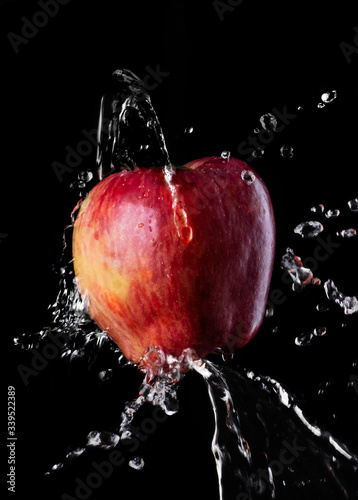 red fresh Apple of the "Red chief" variety on a solid black background Splash of water