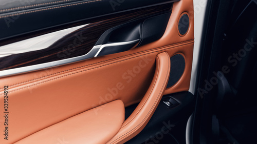 Car interior. Car door interior trim. Soft focus. Black and brown leather car interior. Modern car illuminated dashboard. Luxurious instrument cluster. Close up shot of automobile instrument panel