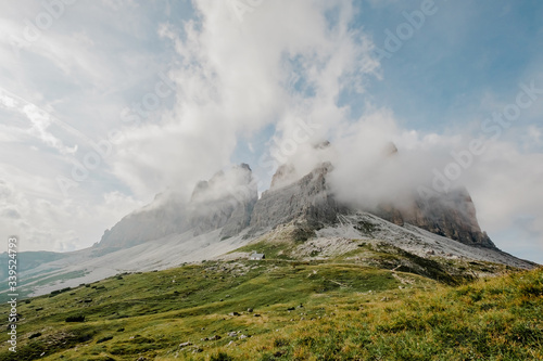 Italian Dolomites, Tre Cime - Rifugio Lavaredo - stony road around Tre Cime .Peak in the clouds. Aerial shot. Beautiful sky and clouds behinds the moutains and valley. 