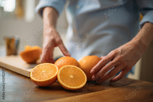 Young woman making juice from fresh oranges at home