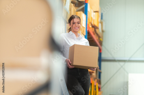 Woman is working in a warehouse with a box in her hand