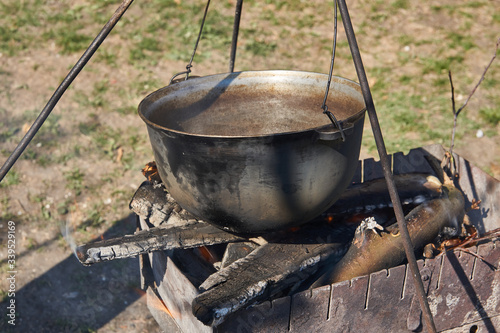 Food is prepared in a cauldron. The bowler boils at the stake, in the background is a flower country bed.