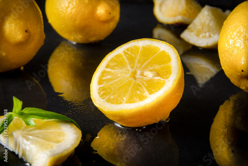 lemons with Basil on a wet black , half, slices and whole  citrus, close up