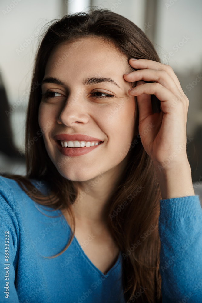 Image of young joyful woman looking aside and smiling while sitting Image of young joyful woman looking aside and smiling while sitting