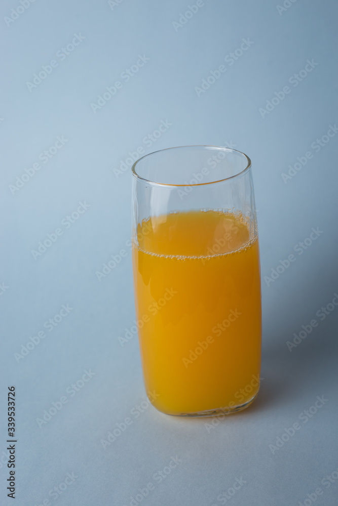 Jugo de nanja fresco con trozos de naranja sobre un fondo azul Jugo de nanja fresco con trozos de naranja sobre un fondo azul