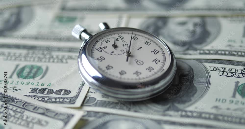 The stopwatch lies on the dollars. Time is money concept. The stopwatch lies on the dollars. Time is money concept.