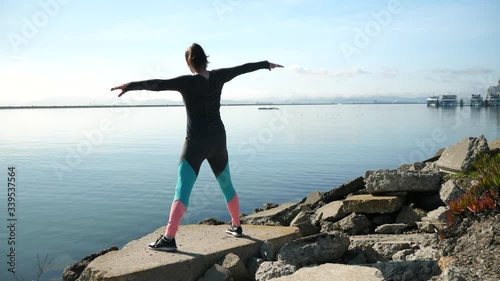 A girl stretching on the shoreline looking out into the San Franciso Bay while balancing on a rock. photo