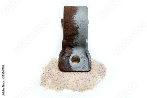 The overgrown rusty cast iron part partly sand blasted together with sand isolated in a white background. 