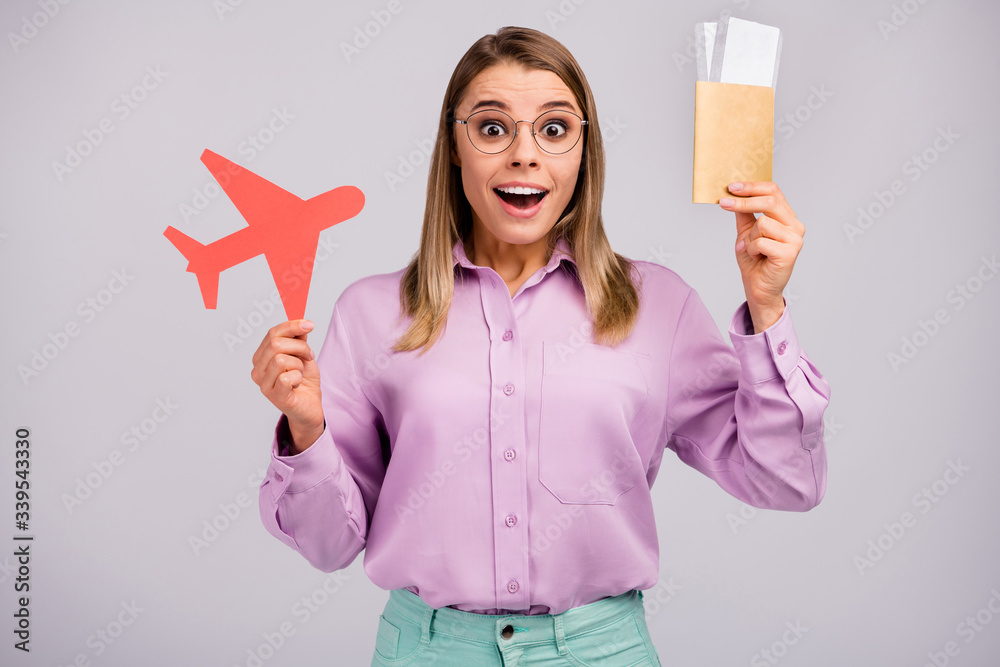 Portrait of astonished crazy girl impressed tourism win lottery hold red paper card plane visa scream wow omg wear stylish outfit isolated over gray color background Portrait of astonished crazy girl impressed tourism win lottery hold red paper card plane visa scream wow omg wear stylish outfit isolated over gray color background
