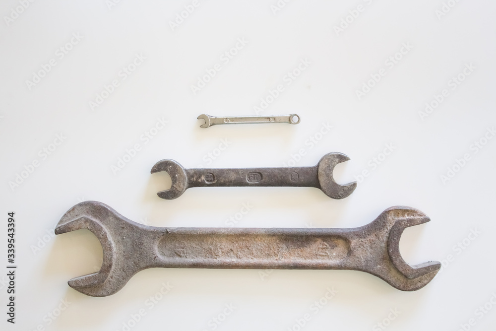 Old rusty wrench on a white and metal background. several wrenches of different sizes. Card with copy space for text Old rusty wrench on a white and metal background. several wrenches of different sizes. Card with copy space for text