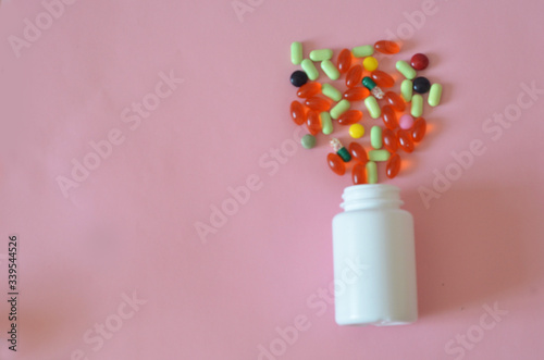 Assorted pharmaceutical medicine pills, tablets and capsules and bottle on pink background. Copy space for text