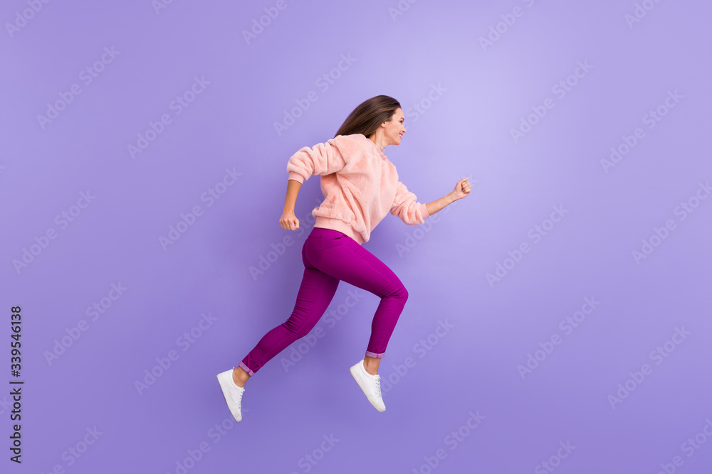 Full length profile photo of active lady jumping high up rushing speed shopping sale black friday wear casual warm fluffy sweater pants shoes isolated purple color background Full length profile photo of active lady jumping high up rushing speed shopping sale black friday wear casual warm fluffy sweater pants shoes isolated purple color background