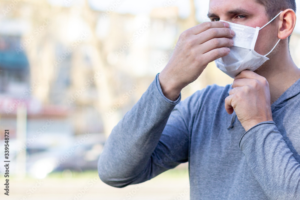 Caucasian man putting on a face medical mask on the street outdoor Caucasian man putting on a face medical mask on the street outdoor