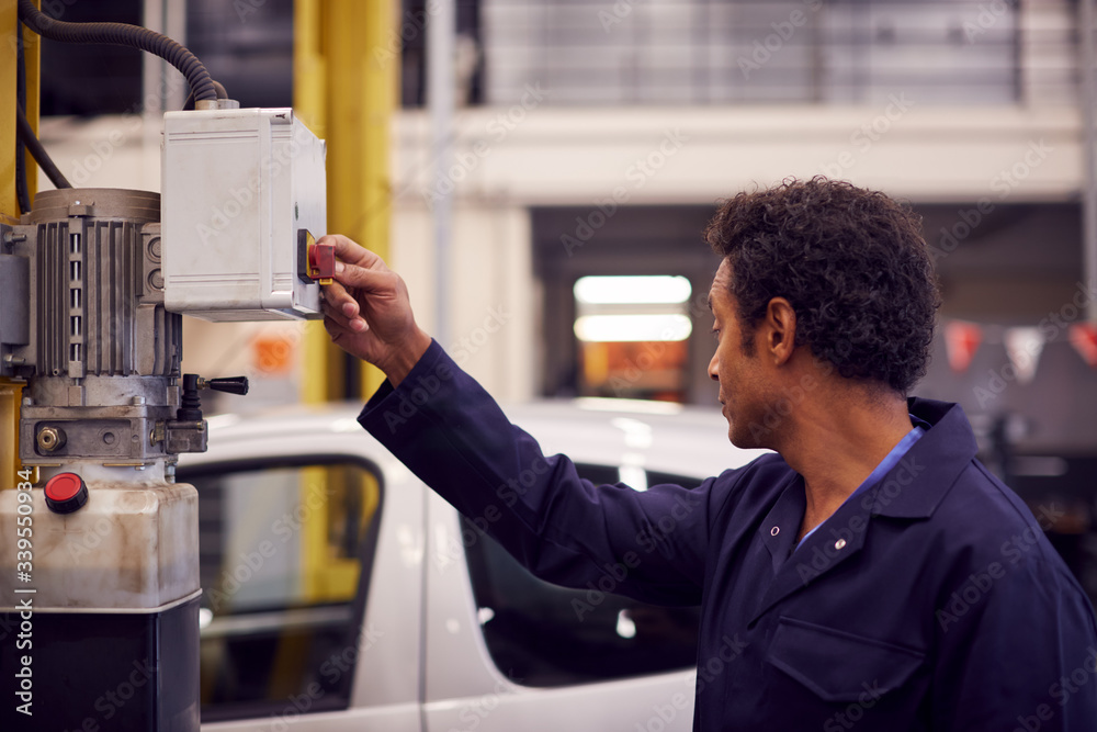 Male Motor Mechanic Raising Car On Hydraulic Lift In Garage Male Motor Mechanic Raising Car On Hydraulic Lift In Garage