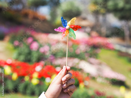 Close up hand holding colorful pinwheel over flower field blur background.