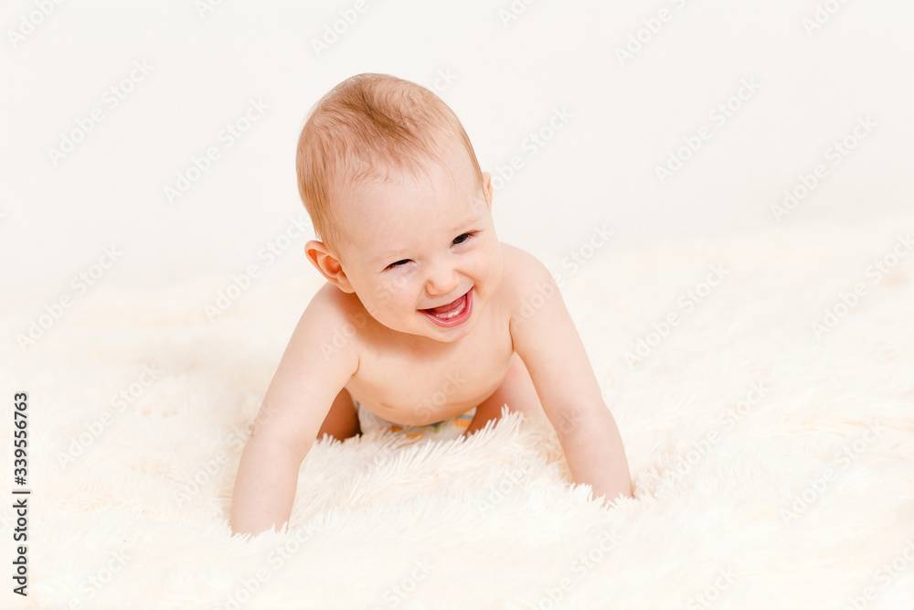 a naked Caucasian eight-month-old baby crawls on a bed on a white background . children under one year old a naked Caucasian eight-month-old baby crawls on a bed on a white background . children under one year old