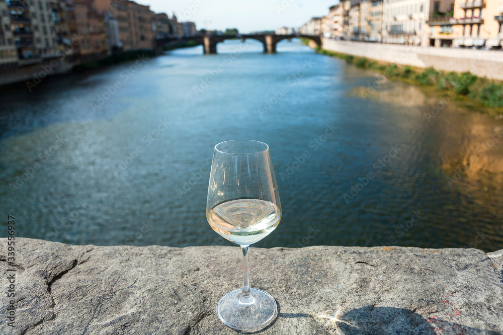 Obraz premium Lonely wine glass in distance from people, on bridge of Florence, Italy. Empty european city