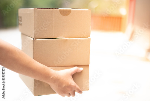 Delivery man hand carrying cardboard box packaging for logistic shipping.