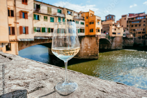 Lonely white wine glass in distance from people, past famous bridge of Florence, Italy. Empty european city