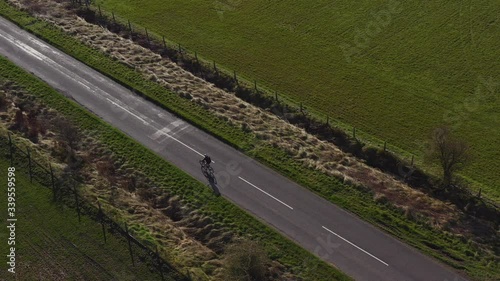 Drone footage of a person mountain biking along an empty country road on a sunny morning in North Yorkshire England completely isolated photo