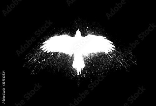 White silhouette of a flying raven with spread wings with paint splashes, splatters and blots isolated on a black background. photo