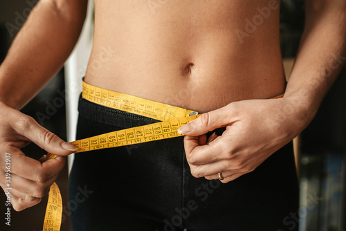 woman measuring her waist with a tape before coming summer season photo