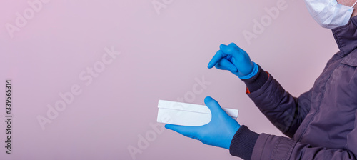 Courier, delivery man in medical blue gloves and mask, safe delivers online purchases in white box with copy space during the coronavirus epidemic, COVID-19 ncov. Stay at home shopping online concept.