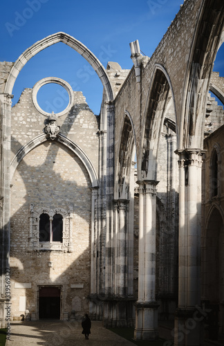 Small distant walking woman in the ruins of the ancient convent of Carmo in Lisbon, Portugal, roofless church open to sky survived to the 1755 earthquake in the city