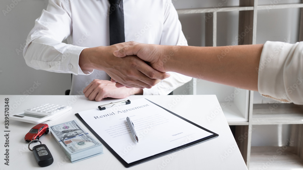 Car sales agent and client shaking hand after finishing signed the car rental agreement in the office. Car sales agent and client shaking hand after finishing signed the car rental agreement in the office.