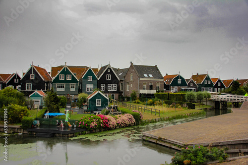 Colorful Marken homes with a lawn garden and the canal passing in cloudy weather