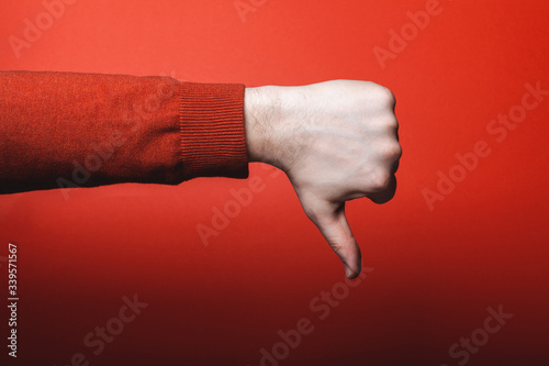 Man hand shows thumb down on red background.